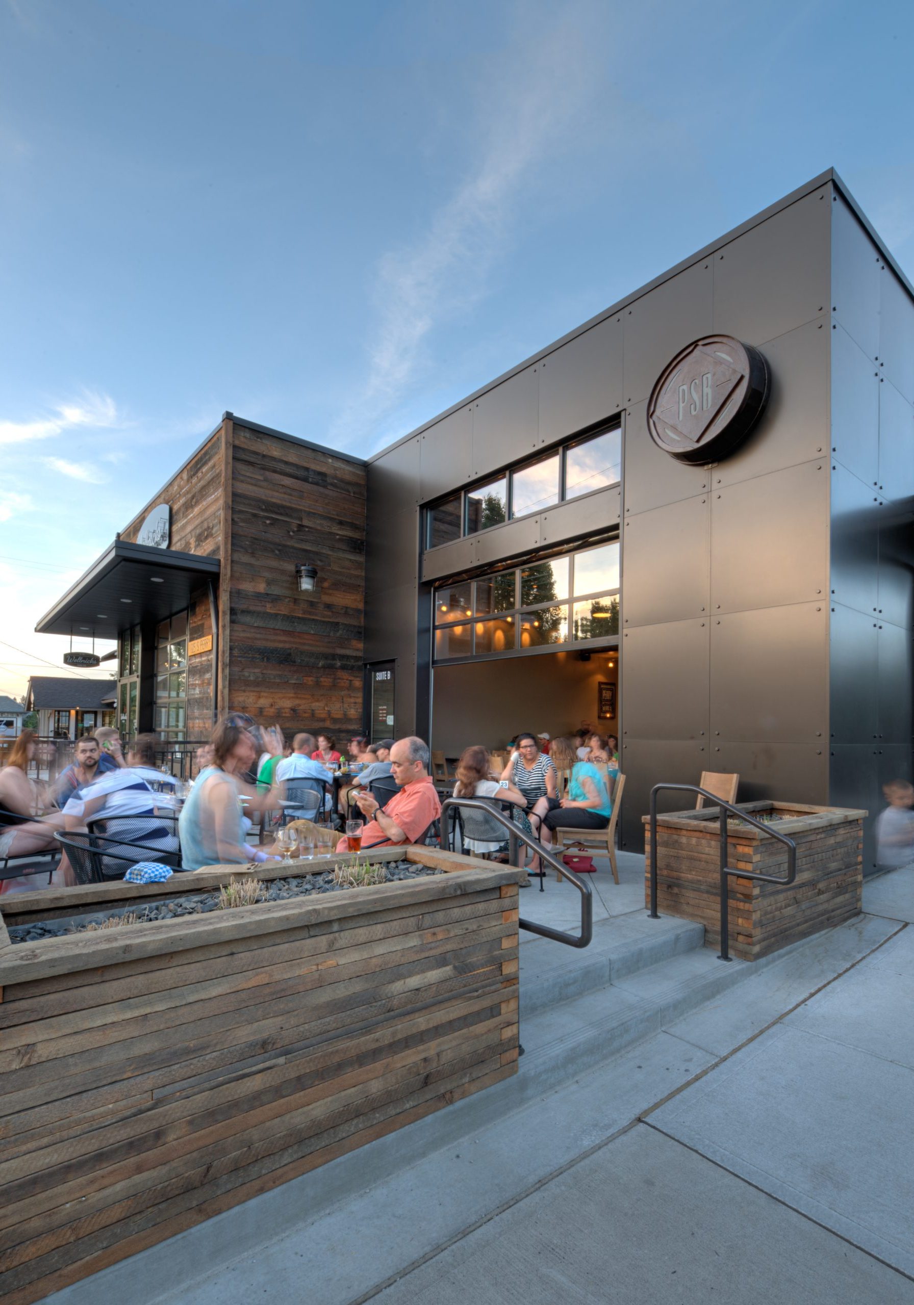 Perry Street brewing exterior including outdoor patio, glass garage door half open and main signage